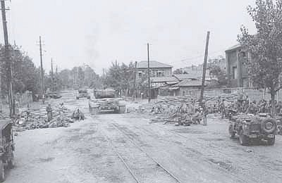 Tanks of the 5th Marine Regiment passing through a demolished barricade on the outskirts of Seoul